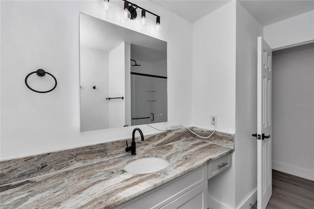 bathroom with vanity, a shower with shower door, and hardwood / wood-style floors