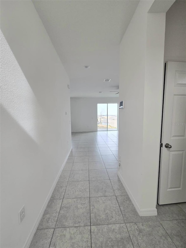 hall featuring light tile patterned floors and baseboards