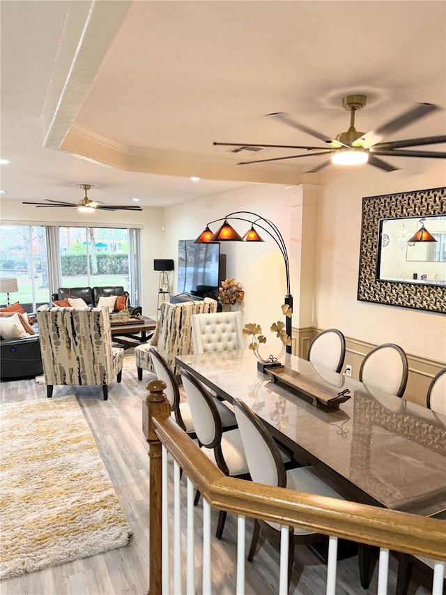 dining area with light hardwood / wood-style floors, a tray ceiling, and ceiling fan