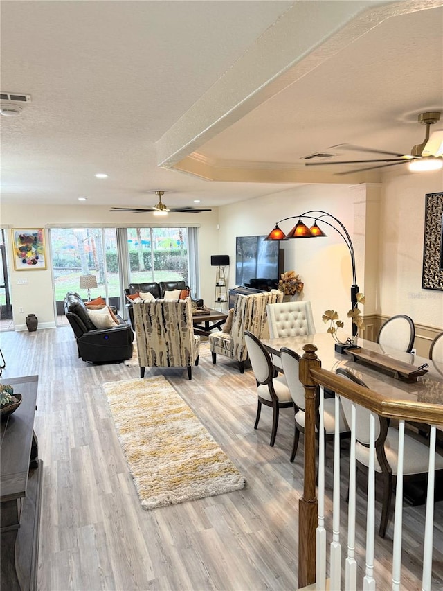 dining area featuring light hardwood / wood-style floors, a raised ceiling, and ceiling fan