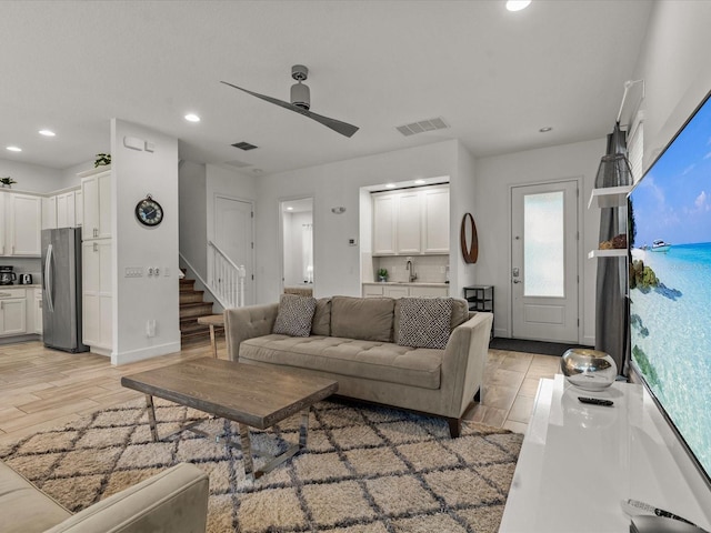 living room featuring ceiling fan, sink, and light wood-type flooring