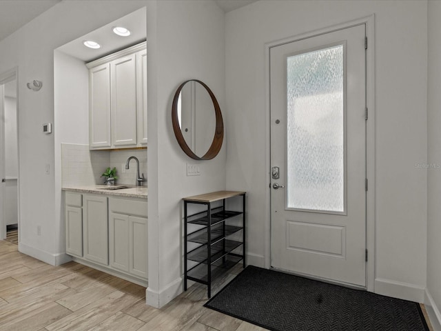 foyer featuring sink, light hardwood / wood-style floors, and a healthy amount of sunlight