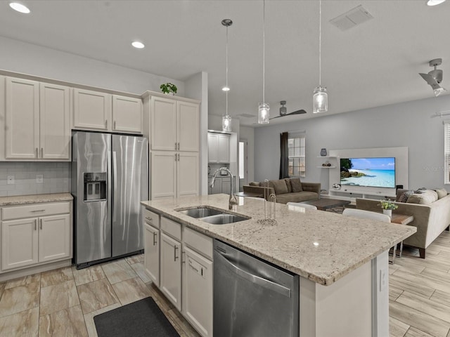 kitchen with pendant lighting, white cabinetry, sink, a kitchen island with sink, and stainless steel appliances