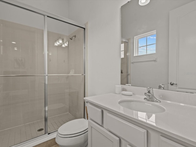 bathroom featuring vanity, toilet, and a shower with shower door