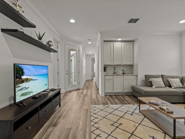 living room with ornamental molding and light hardwood / wood-style floors