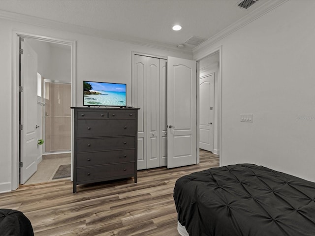 bedroom featuring crown molding, wood-type flooring, ensuite bath, and a closet