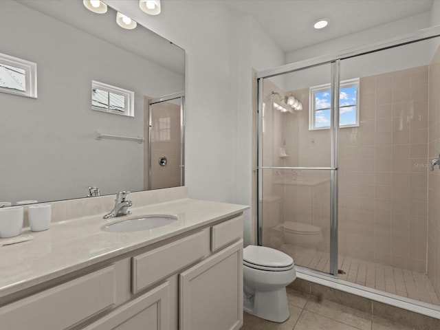 bathroom with a shower with door, vanity, tile patterned floors, and toilet