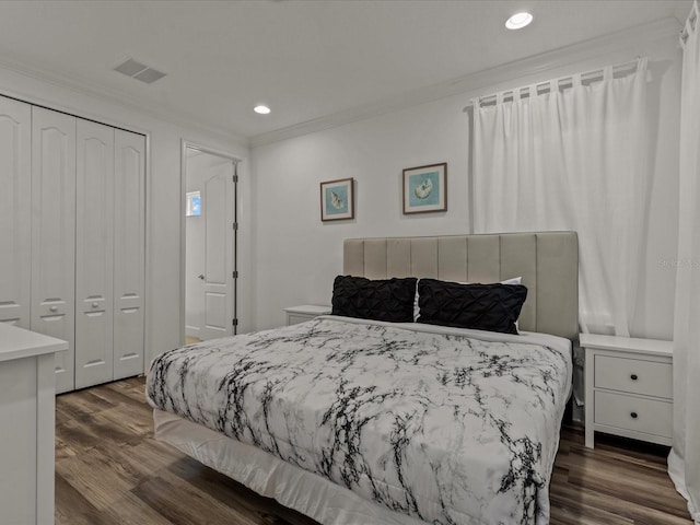 bedroom with dark hardwood / wood-style flooring, crown molding, and a closet