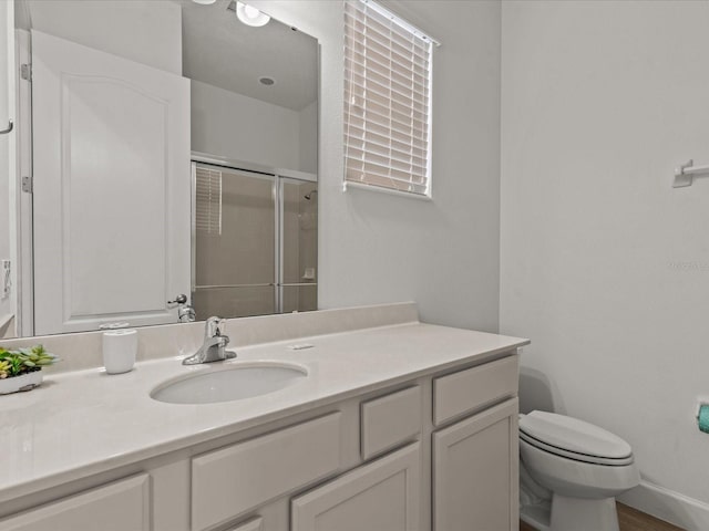 bathroom featuring vanity, toilet, and a shower with door