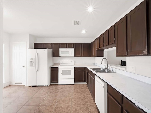 kitchen featuring light tile patterned floors, sink, dark brown cabinetry, and white appliances