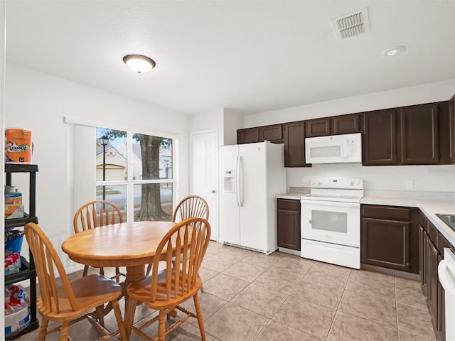 kitchen featuring white appliances, light tile patterned floors, and dark brown cabinetry