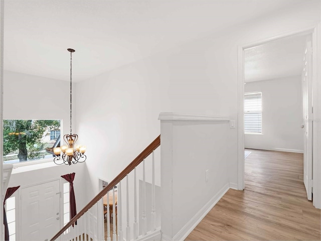 hall with light hardwood / wood-style flooring and a notable chandelier