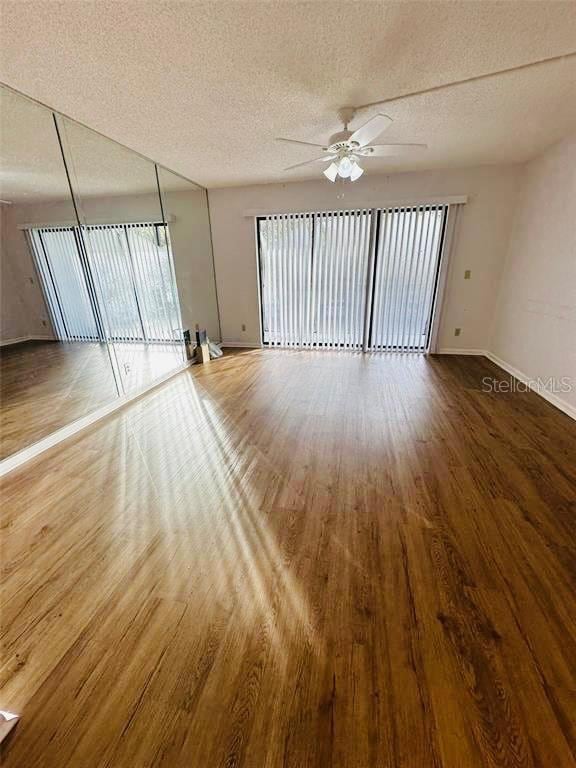 unfurnished room featuring ceiling fan, wood-type flooring, plenty of natural light, and a textured ceiling