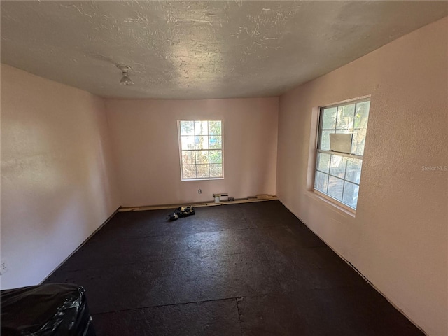 unfurnished room with a textured ceiling and a healthy amount of sunlight