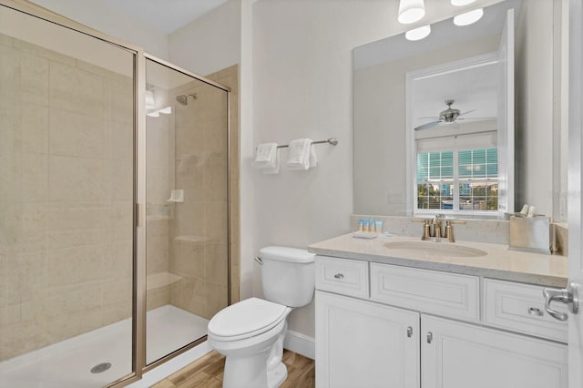 bathroom featuring toilet, a shower with shower door, wood-type flooring, vanity, and ceiling fan