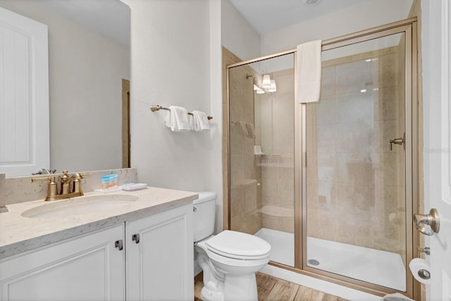 bathroom with a shower with door, vanity, hardwood / wood-style floors, and toilet