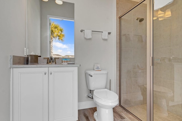 bathroom featuring vanity, wood-type flooring, a shower with shower door, and toilet