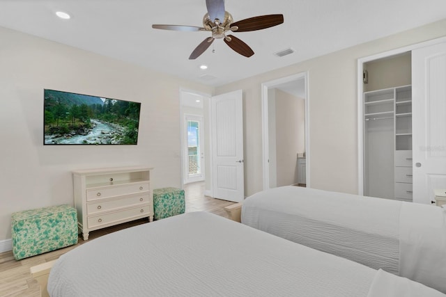 bedroom with a walk in closet, a closet, ceiling fan, and light wood-type flooring