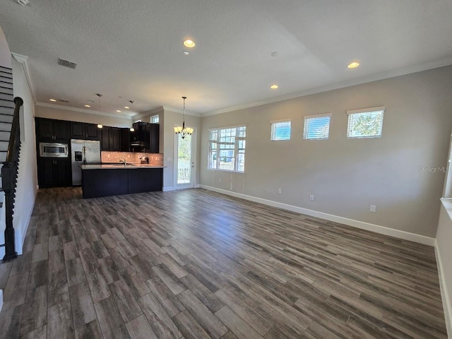 unfurnished living room featuring ornamental molding, dark wood-type flooring, and a notable chandelier