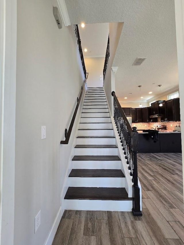 stairs featuring wood-type flooring and a textured ceiling