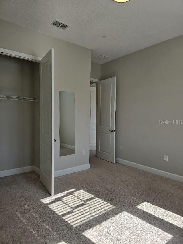 unfurnished bedroom with carpet, a closet, and a textured ceiling