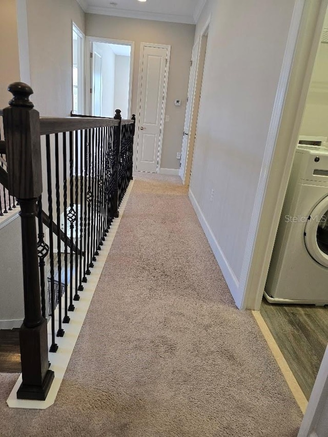 corridor featuring ornamental molding, washer / dryer, and carpet floors