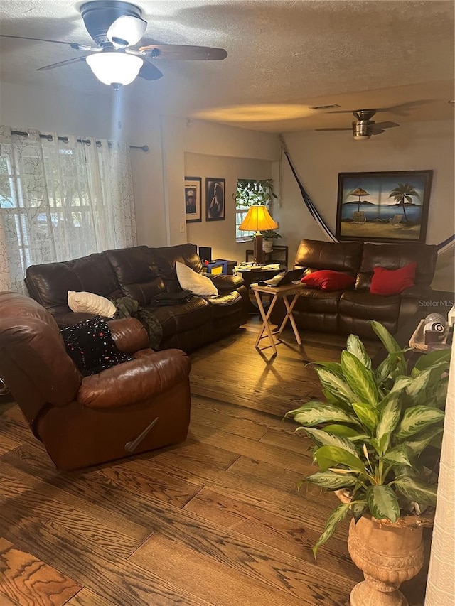 living room featuring ceiling fan, a textured ceiling, and wood-type flooring