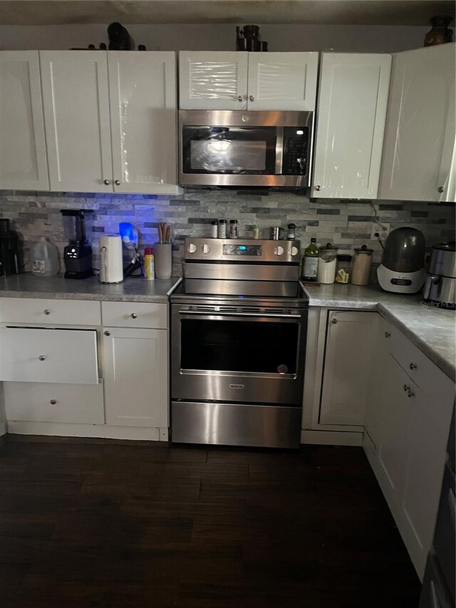 kitchen with stainless steel appliances, white cabinetry, dark hardwood / wood-style floors, and decorative backsplash