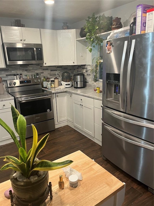 kitchen with backsplash, white cabinets, dark wood-type flooring, and stainless steel appliances