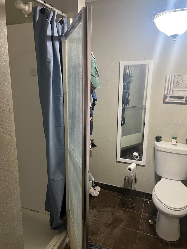 bathroom featuring toilet, walk in shower, and tile patterned flooring