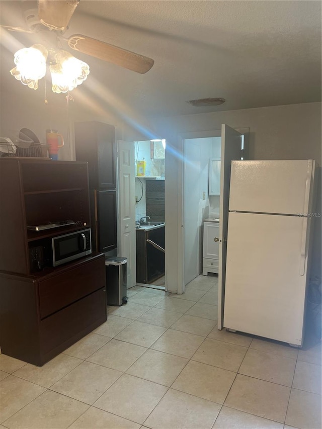 kitchen with sink, white refrigerator, light tile patterned floors, and ceiling fan