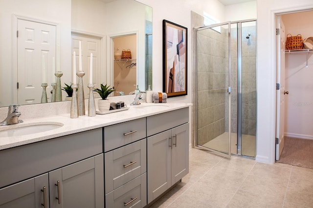 full bathroom featuring a spacious closet, tile patterned floors, a stall shower, and a sink