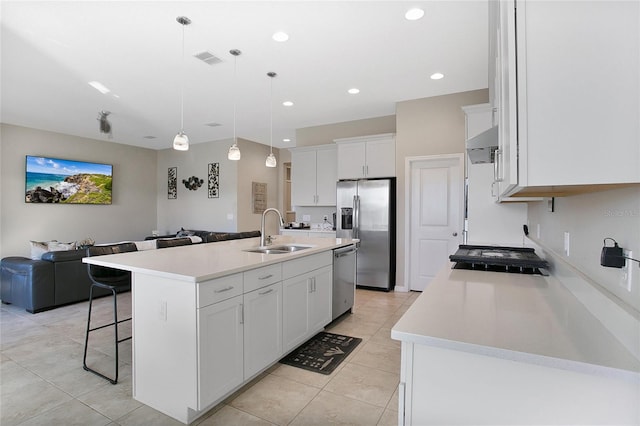 kitchen with hanging light fixtures, sink, white cabinetry, a kitchen island with sink, and stainless steel appliances