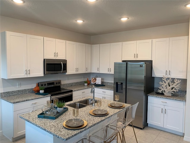 kitchen with light stone counters, stainless steel appliances, sink, and white cabinets