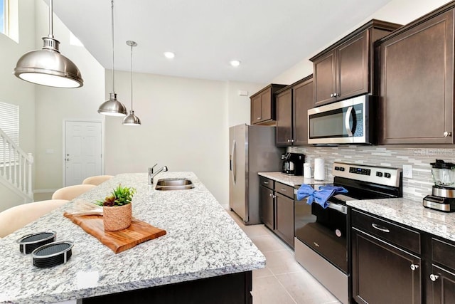 kitchen featuring sink, backsplash, appliances with stainless steel finishes, and a kitchen island with sink