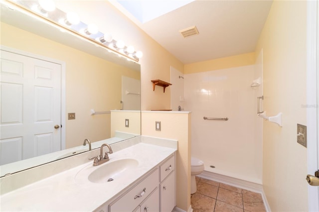 bathroom featuring toilet, vanity, tile patterned flooring, and walk in shower