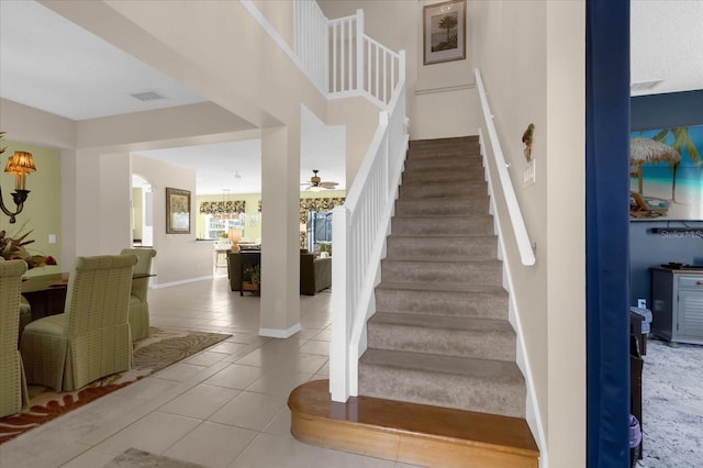 stairway featuring ceiling fan and tile patterned floors