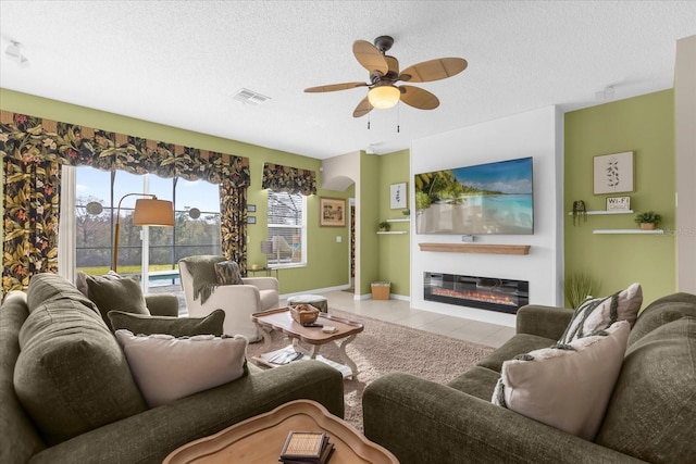 tiled living room with ceiling fan and a textured ceiling