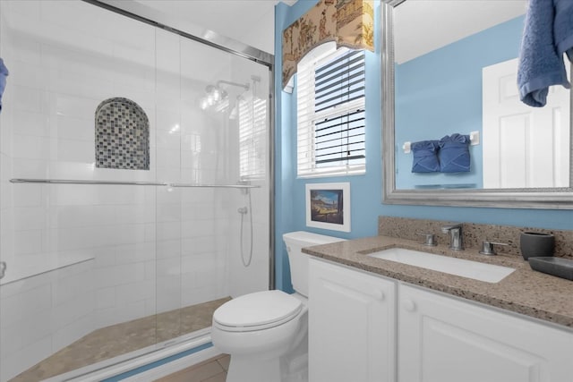 bathroom featuring vanity, a shower with shower door, tile patterned floors, and toilet