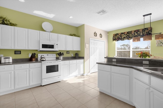 kitchen with light tile patterned flooring, white cabinets, white appliances, and decorative light fixtures