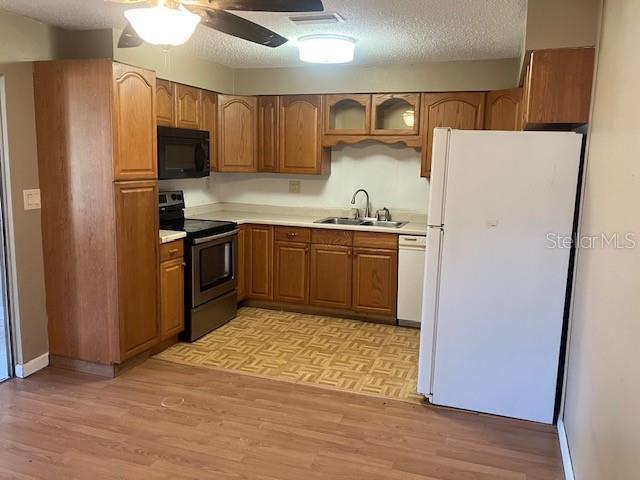 kitchen with ceiling fan, white appliances, light wood-type flooring, a textured ceiling, and sink