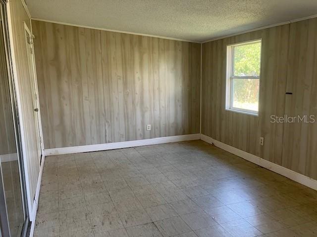 empty room featuring a textured ceiling and wood walls