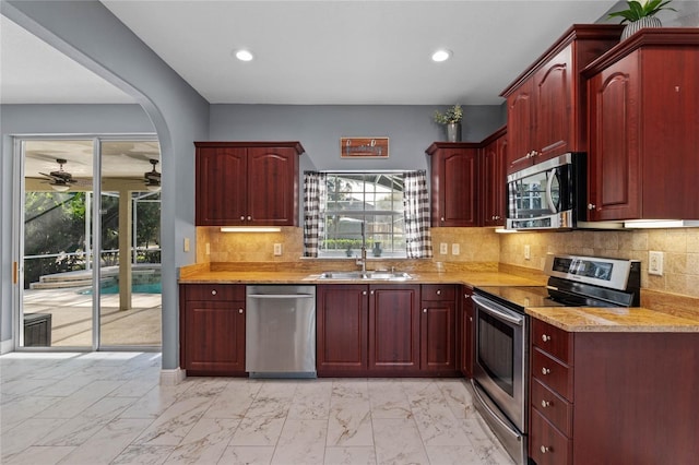 kitchen with marble finish floor, a wealth of natural light, appliances with stainless steel finishes, a sink, and dark brown cabinets