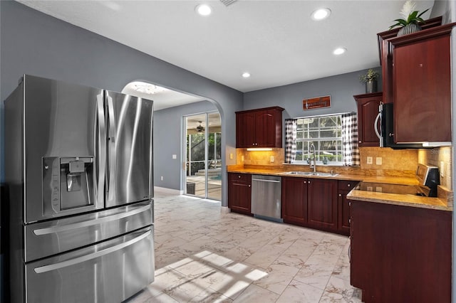 kitchen featuring marble finish floor, arched walkways, stainless steel appliances, and a wealth of natural light