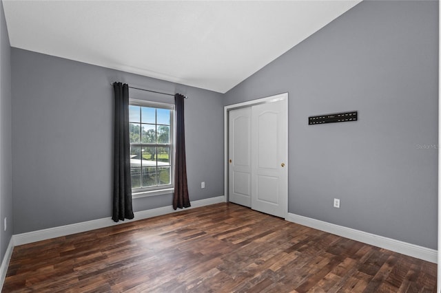 unfurnished room featuring lofted ceiling, baseboards, and wood finished floors