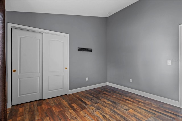 unfurnished bedroom featuring a closet, baseboards, and dark wood-type flooring