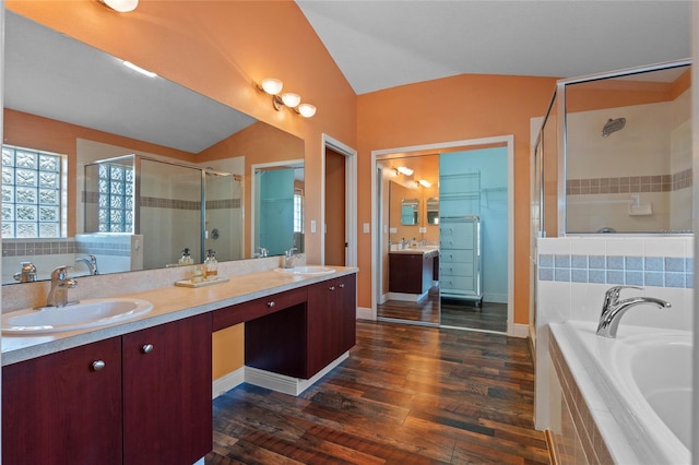 bathroom with a stall shower, lofted ceiling, a sink, and a bath