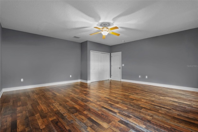 spare room with dark wood-style floors, visible vents, baseboards, and a ceiling fan