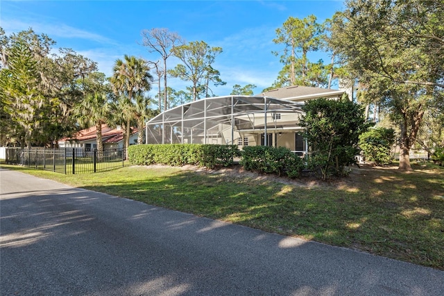 view of front of house featuring glass enclosure, fence, and a front yard