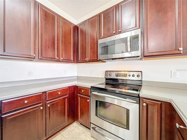 kitchen featuring stainless steel appliances, light tile patterned floors, and a textured ceiling